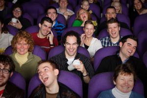 A large audience in a darkened movie theater.